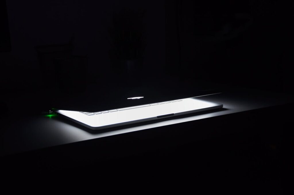 pexels-photo-633409 A dramatic, low-light image of a slightly open laptop with glowing keys on a dark desk.